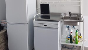 A compact kitchen with a refrigerator, dishwasher, and a small countertop with a sink and various items. - Penthouse between sea and mountains (CN)