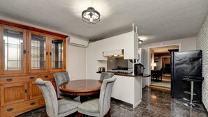 A modern kitchen with a dining area, featuring a wooden cabinet, a round table, and grey upholstered chairs.