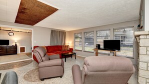 A living room with a red sofa, two armchairs, a coffee table, a TV, and a fireplace.