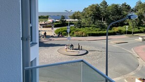A view from a balcony overlooking a roundabout with a pedestrian island, a street lamp, and a signpost. - Vacation apartment Sunrise 10 with balcony and sea view, Cuxhaven Duhner Allee (Cuxhaven)