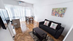 Una sala moderna con un sofá, una mesa de centro y un comedor con sillas y una mesa.