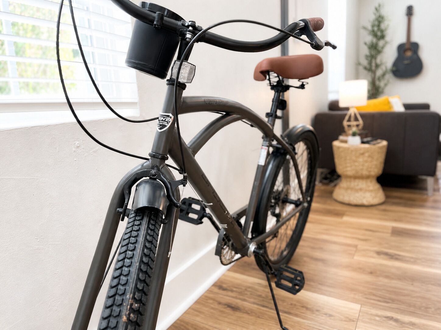 A stationary bicycle in a room with a wooden floor, a sofa, and a guitar in the background.