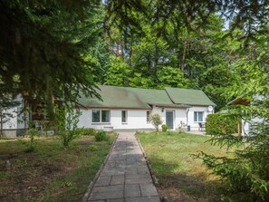A single-story house with a green roof, a front porch, and a pathway leading to the entrance. - Two bungalows with their own jetty 5 minutes from the lake (Rheinsberg)