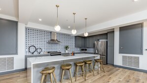 Una cocina moderna con una isla central, taburetes de bar, electrodomésticos de acero inoxidable y un salpicadero decorativo.