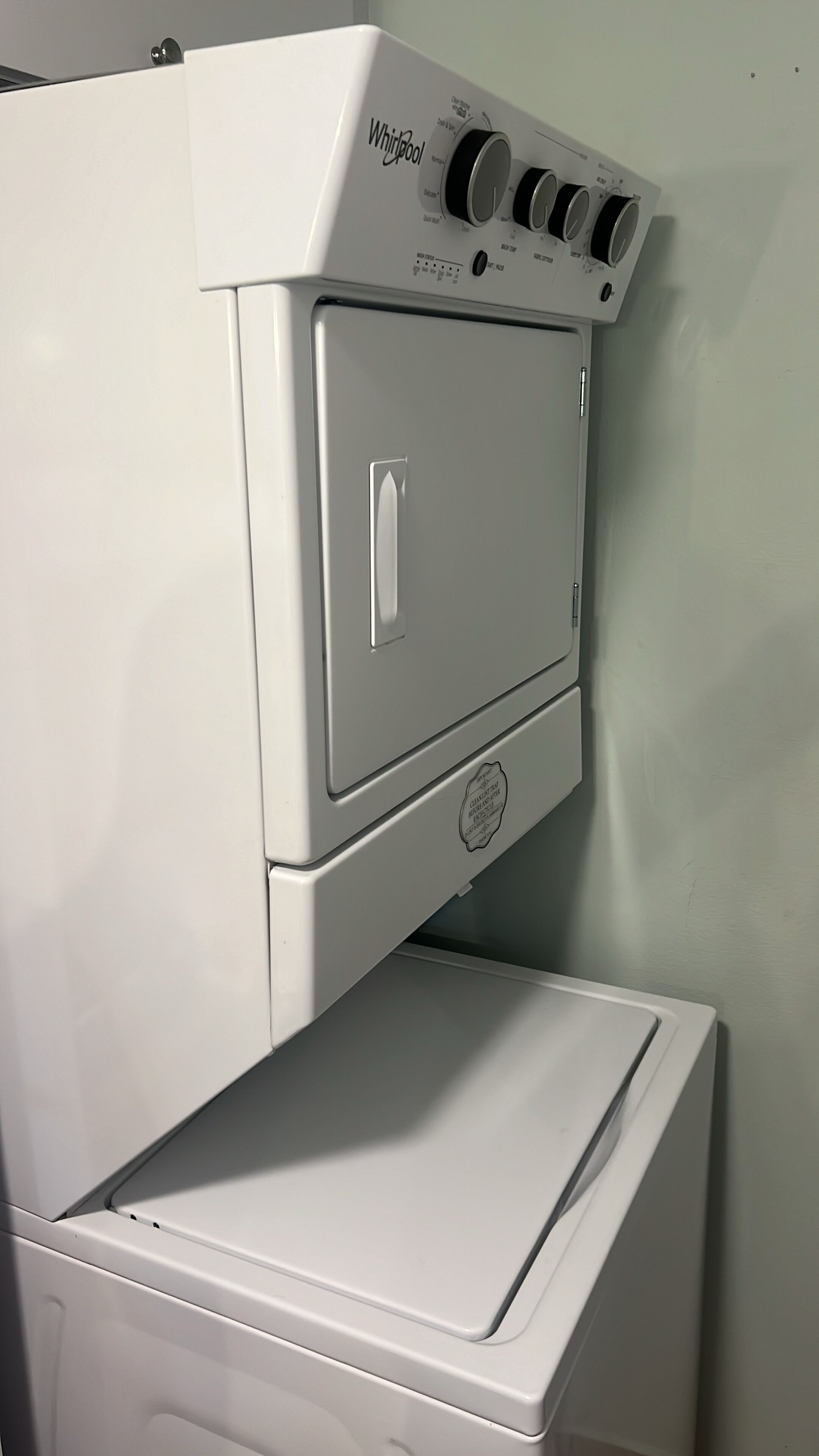 A Whirlpool washer and dryer stacked together in a corner.