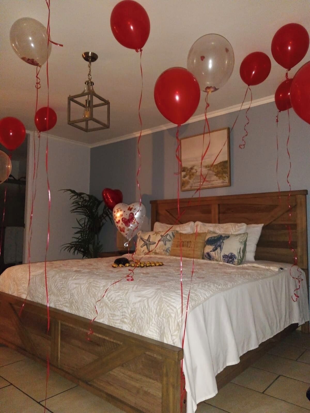Una camera da letto con un letto di legno, un comodino, una pianta in vaso e palloncini.