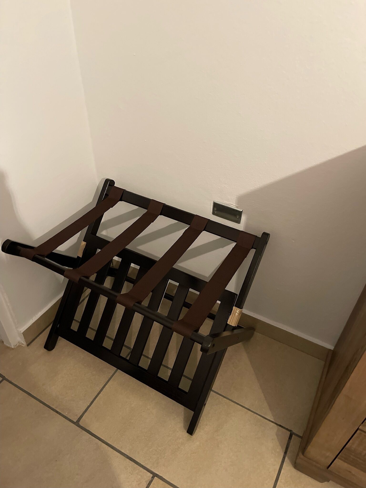 A corner of a room with a wooden chair and a small table against the wall.