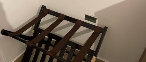 A corner of a room with a wooden chair and a small table against the wall.
