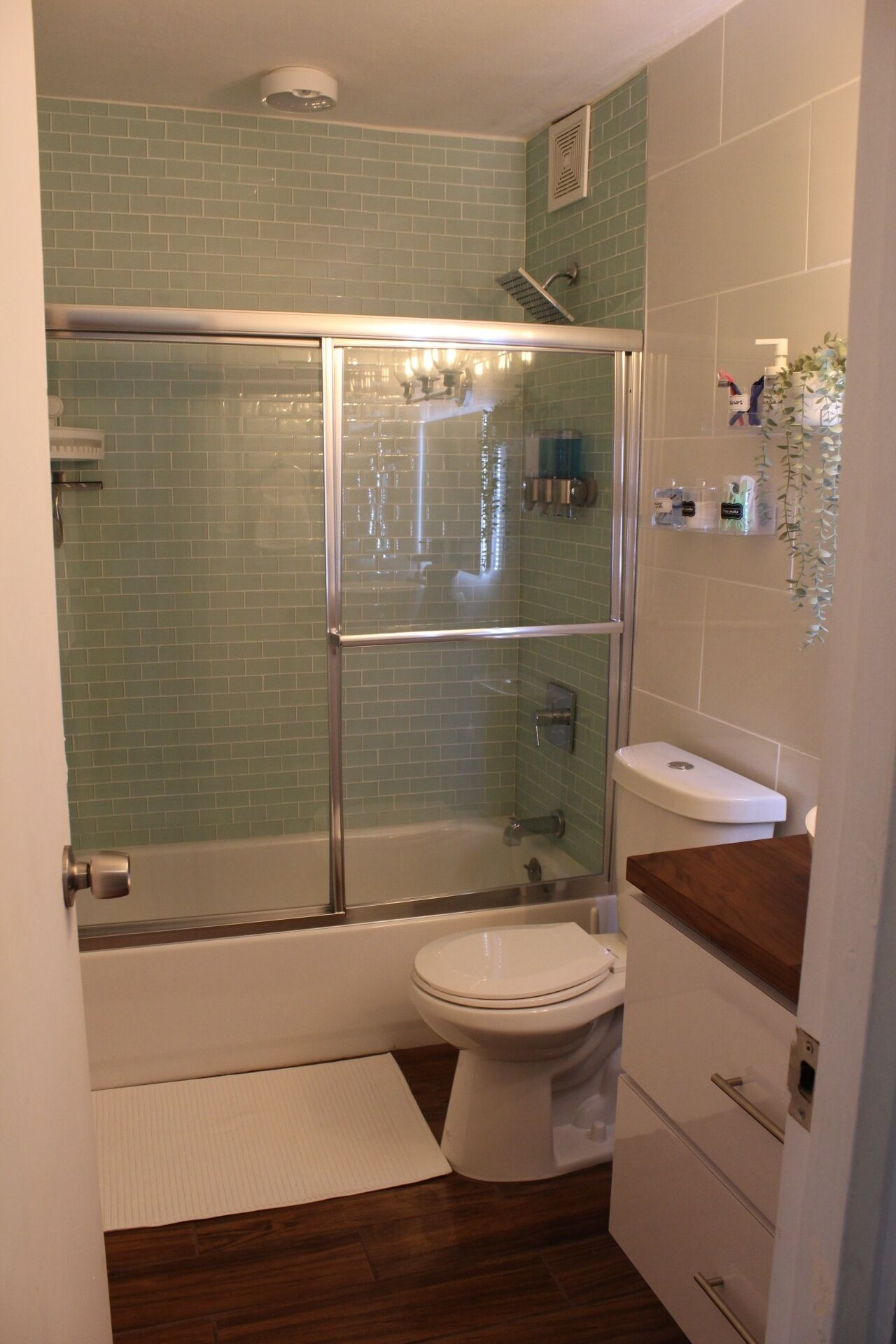 Ein Badezimmer mit einer Duschkabine, einer weißen Toilette, einem Waschbecken und einer Holzauslage.