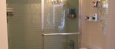 Ein Badezimmer mit einer Duschkabine, einer weißen Toilette, einem Waschbecken und einer Holzauslage.