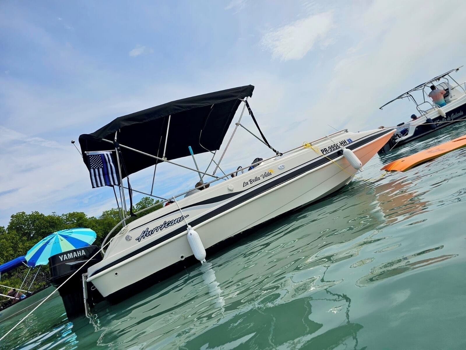 Un barco llamado 'La Bella Vida' amarrado en un puerto deportivo, con una sombrilla Yamaha cerca.