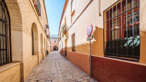 A narrow cobblestone street flanked by buildings with barred windows and a no parking sign.