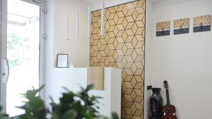 Ein Empfangsbereich im modernen Stil, mit einer Wand in geometrischem Muster, einer Rezeption und einer Gitarre an der Wand.