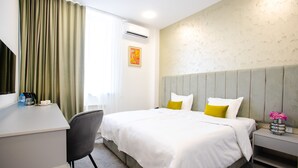 Ein Hotelzimmer mit Bett, Nachttisch, Stuhl und Schreibtisch, auf dem sich eine Wasserflasche und ein Becher befinden.