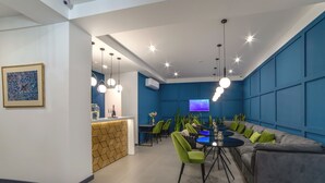 Eine moderne Lounge mit einer Couch, Sesseln, einem runden Tisch und einem Fernseher.