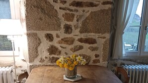Ein Esstisch mit Stühlen, eine Blumenvase, eine Lampe und eine Steinwand.