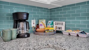 Eine Küchenarbeitsplatte mit Kaffeemaschine, Kaffeetassen, einer Schale mit Kaffeebohnen, einem Schild mit der Aufschrift 'COFFEE TIME' und einem Kaffee-Dekorationsschild.