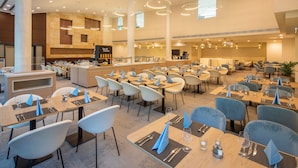 Un espace de restauration spacieux et bien éclairé, avec de nombreuses tables et chaises, un comptoir central et un aménagement intérieur moderne.