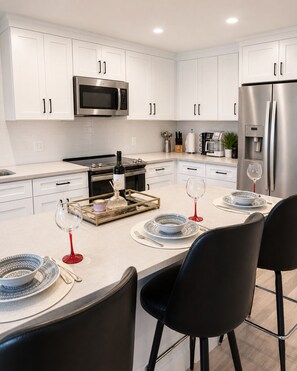 A modern kitchen with white cabinets, stainless steel appliances, and a central island with seating.