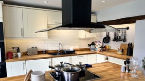 Een moderne keuken met witte kastjes, een houten aanrecht, een gasfornuis en diverse keukenapparaten.