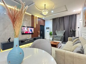 Un salon moderne comprenant un téléviseur, un canapé, une table basse et des plantes décoratives.