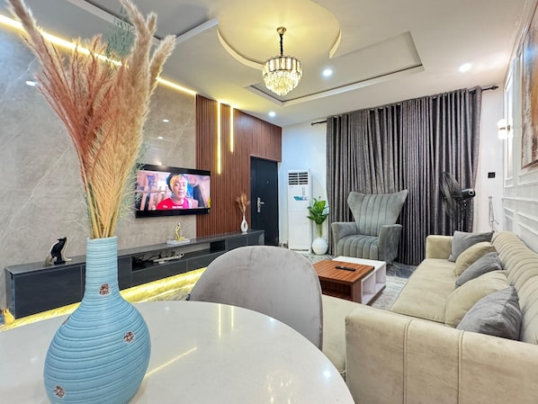 A modern living room with a TV, sofa, coffee table, and decorative plants.
