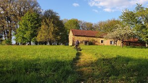 Ein Haus aus Stein mit rotem Dach, umgeben von üppigem Grün und Bäumen.