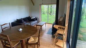 Ein modernes Interieur mit einem Holztisch, Stühlen, einer Couch und einer großen Schiebeglastür, die zu einem Garten führt.