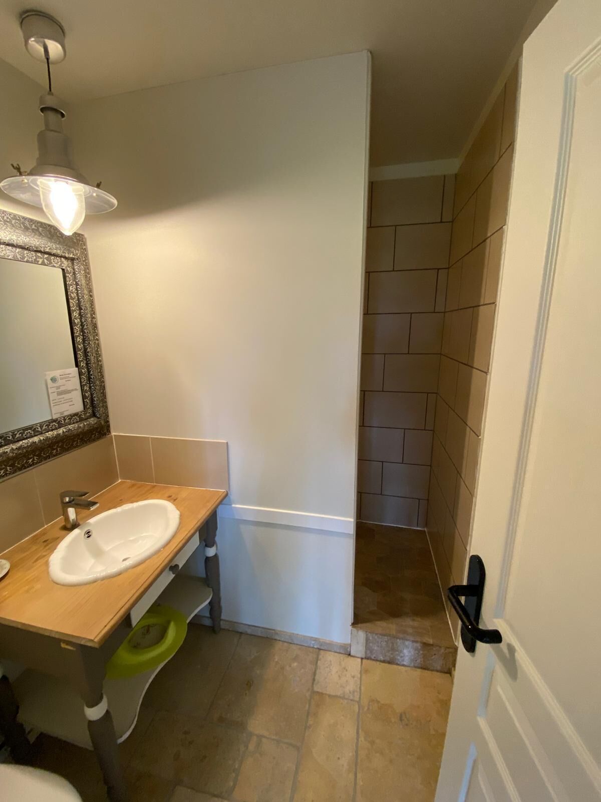 A bathroom with a wooden vanity, a white sink, a mirror with a decorative frame, and a light fixture above the mirror.