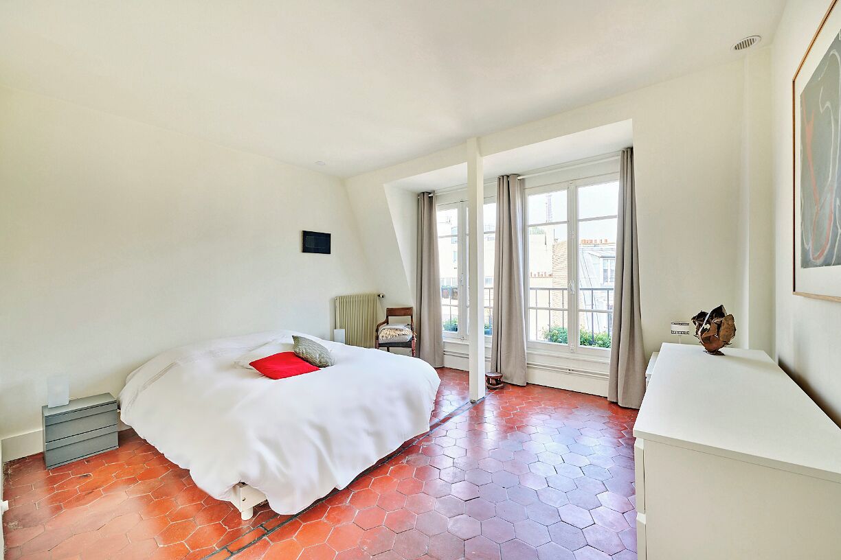 A bedroom with a bed, a desk, and a window with curtains.