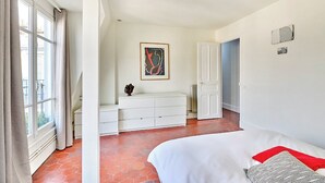 A bedroom with a bed, a dresser, a radiator, and a painting on the wall.