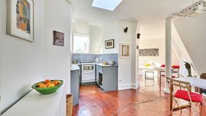 A modern kitchen with a skylight, a dining area with a table and chairs, and a view of the city through the window.