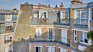 A multi-story residential building with brick facades, white window shutters, and balconies with railings.