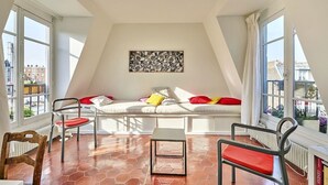 A cozy room with a white sofa, red cushions, a small table, and two chairs.