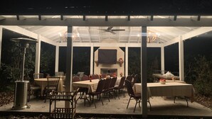 An outdoor covered patio with tables and chairs, a grill, and a ceiling fan.