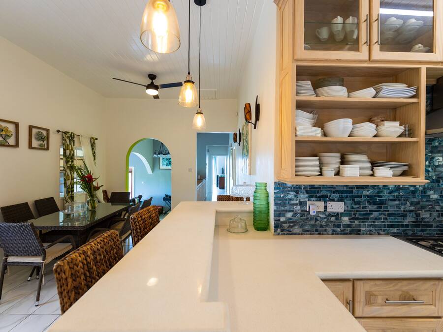 A modern kitchen with a large island, wooden cabinets, and a blue-tiled backsplash.