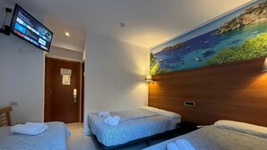 Habitación de hotel con dos camas, un televisor montado en la pared y un mural de una escena costera.