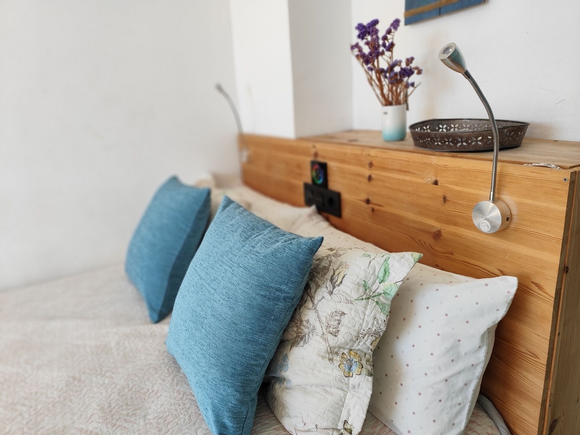 Ein Schlafzimmer mit einem Holzkopfteil, einem Bett mit weißer, gemusterter Bettdecke und zwei Kissen.