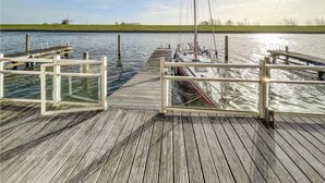 Een houten steiger die zich uitstrekt over een kalm wateroppervlak, met een heldere lucht erboven.