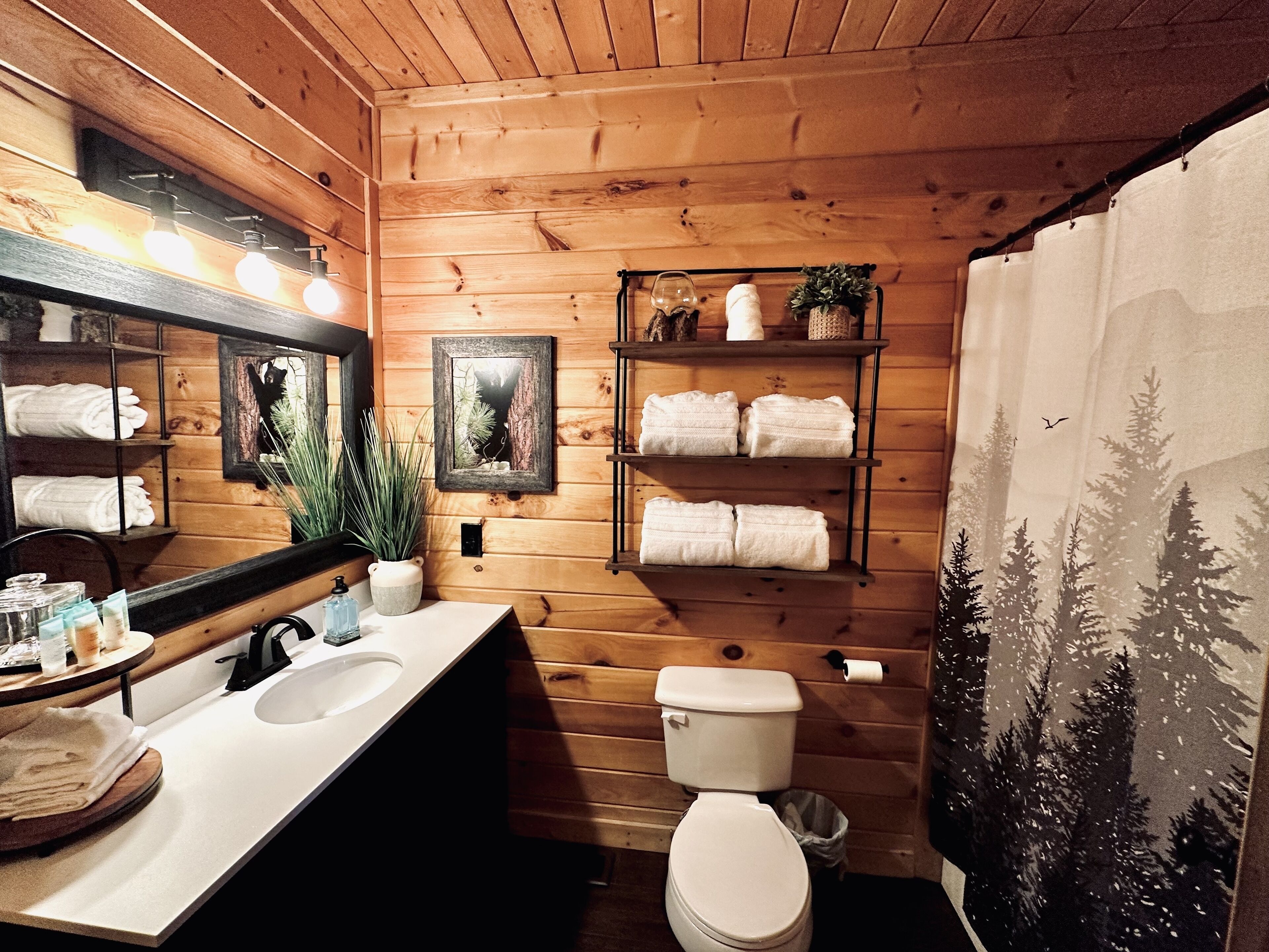 A wooden cabin bathroom with a sink, toilet, shelves with towels, and a mirror.