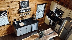 A modern kitchen with wooden walls, a central island with stools, and stainless steel appliances.