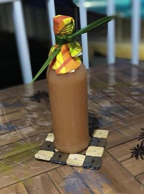 Une bouteille dotée d’un bouchon décoratif et d’une base à motifs, posée sur une surface en bois.