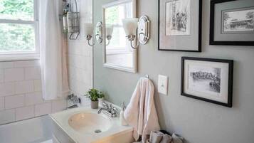 Ein Badezimmer mit Waschbecken, Spiegel, Handtuchhalter und gerahmten Bildern an der Wand.
