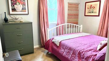 Une chambre à coucher avec un lit, une commode, une chaise et deux fenêtres ornées de rideaux roses.