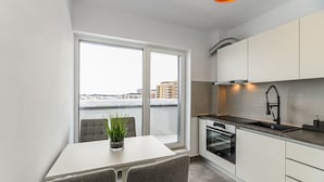 Eine moderne Küche mit einem großen Fenster, einem Essbereich mit Tisch und Stühlen und Blick auf die Stadt.