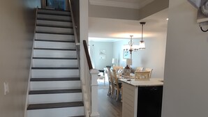A staircase leading to a dining area with a kitchen in the background.