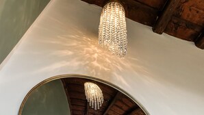 Een ronde spiegel die een kamer weerspiegelt met een kroonluchter en een raam.