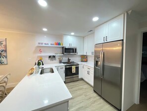 Una cocina moderna con armarios blancos, electrodomésticos de acero inoxidable y una isla central.