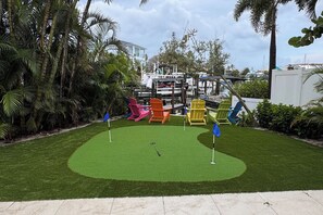 Ein Minigolfplatz mit bunten Stühlen und einem Putting-Green.