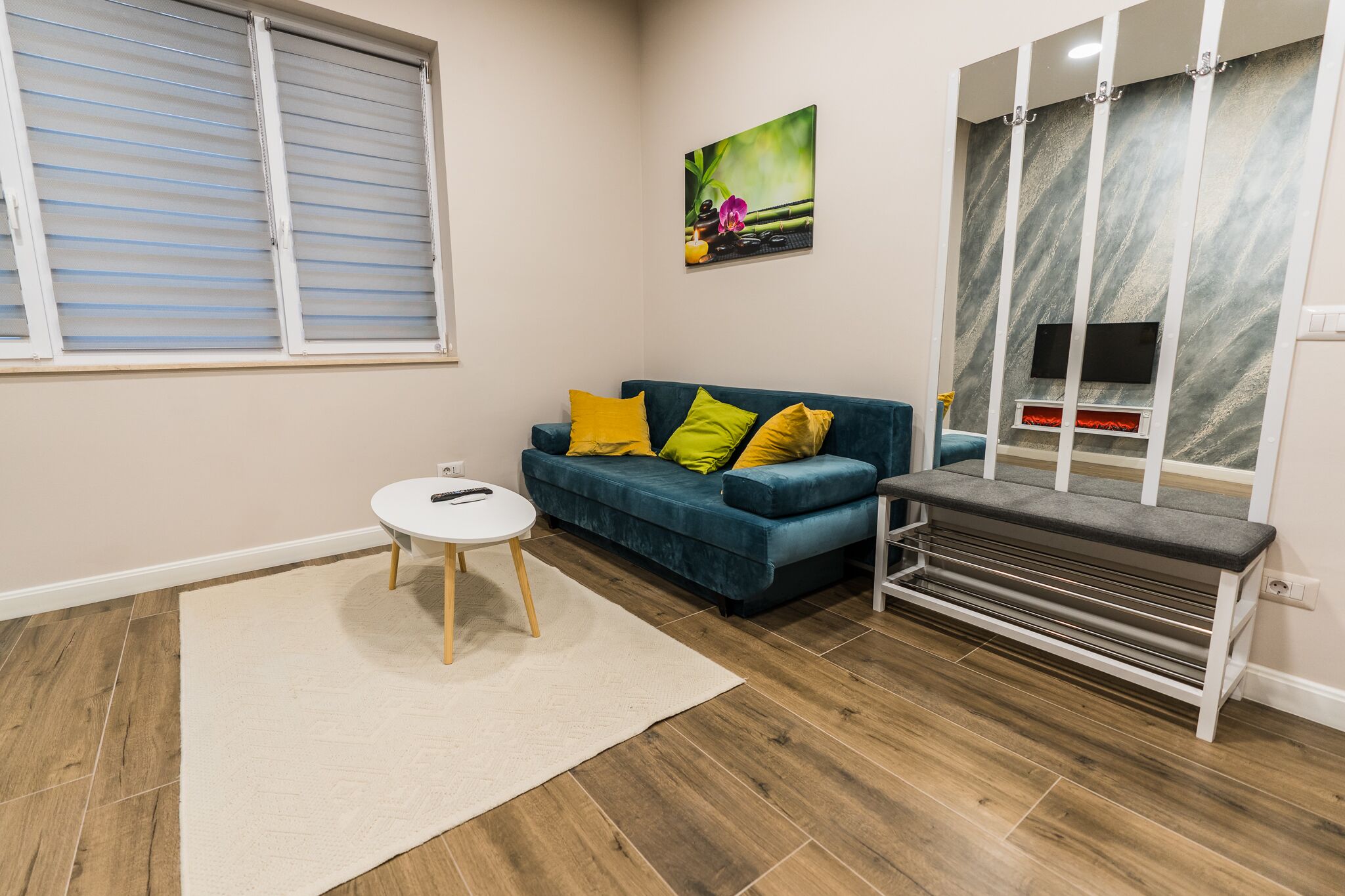 A living room with a blue sofa, a small round table, and a bench.